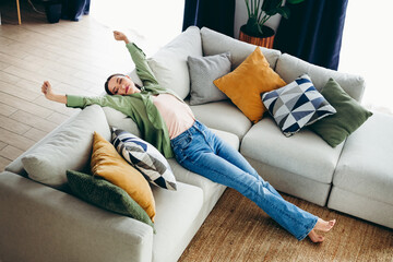Obraz premium Charming woman relaxing on a cozy sofa in a stylish living room enjoying a peaceful moment of leisure at home