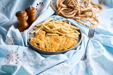 Chicken schnitzel or milanese with fried potatoes in a plate