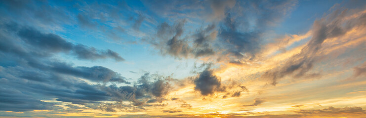 Obraz premium Rain clouds and orange and blue sky,Colorful sunset sky with setting sun behind vivid orange and yellow clouds