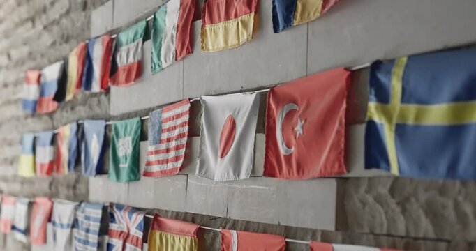 Collection of vibrant national flags hanging neatly along a wall, representing various countries