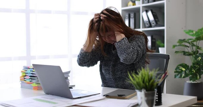 Young asian woman accountant employee Upset stressed guy suffering job problems working on laptop, headache, Bored workaholic headache and stress, migraine, stress relief, chronic pain
