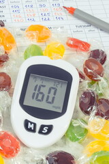 Glucometer with high sugar level, candies and medical form. Measuring and checking sugar level