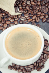 Coffee in white cup and roasted dark coffee beans in bag