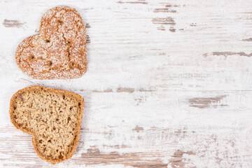 Fresh homemade wholegrain bread in shape of heart for breakfast. Copy space for text on old rustic background