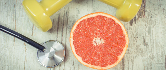 Ripe grapefruit and dumbbells for fitness. Fruits as source minerals and vitamins