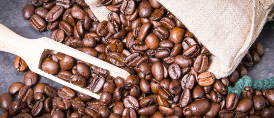 Heap of dark roasted fragrant coffee beans in jute bag