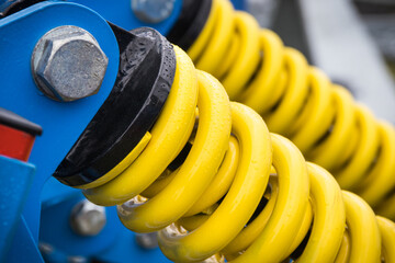 Steel yellow spring as part of blue agricultural machine. Technology