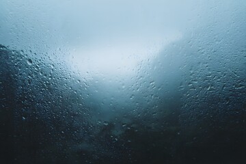 Rainy view of a misty, mountainous landscape through a window with raindrops