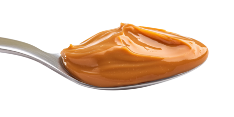 Creamy caramel sauce on a silver spoon against black background Delicious dessert topping concept for confectionery, baking, and sweet treats