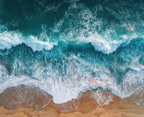 Fototapeta premium Aerial view of ocean waves crashing on a sandy beach, displaying a vibrant turquoise and white contrast