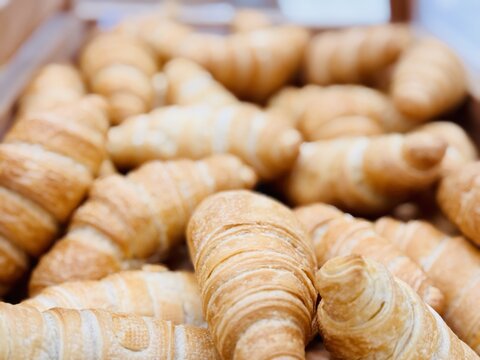A delightful stack of warm, freshly baked, golden croissants is beautifully arranged. An enticing tower of perfectly baked golden croissants, showcasing their flaky and delightful texture beautifully