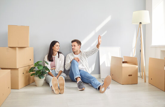 Happy married couple sitting together on the floor, dreaming and planning future while relocating or moving to a new home or estate. Focused on teamwork, aspirations, and a fresh move.