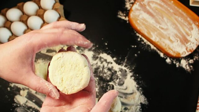 Process of making syrniki. Step 10 - form round syrniki from curd dough. Top view on black surface. Russian cuisine