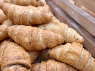 A delightful stack of warm, freshly baked, golden croissants is beautifully arranged. An enticing tower of perfectly baked golden croissants, showcasing their flaky and delightful texture beautifully