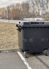 A black plastic container filled with garbage and waste products from residents of an apartment...