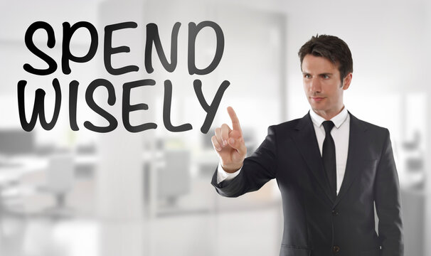 Businessman touching "Spend wisely" text on transparent wipe board in an office