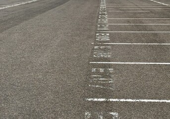 An Empty Parking Lot with Clearly Defined Lines and Markers for Vehicles and Safety. A large, spacious, and empty parking lot featuring welldefined parking lines and detailed asphalt texture