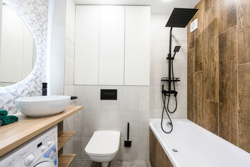Modern bathroom with white fixtures, wood accents, and a black shower system. Clean and minimalist design