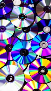 Close up arrangement of compact discs, displaying vibrant, iridescent rainbow colors, data storage devices in a stacked pattern with circular shapes.