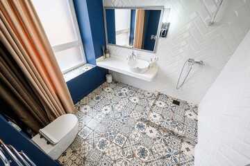 modern bathroom with patterned tile flooring, white herringbone walls, and a blue accent wall...