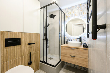 modern bathroom features a shower with black frame, a vanity with a round sink, and unique wall...