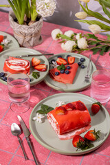 Strawberry dessert rolls and crepes served on pink table setting for spring celebration