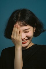 Fototapeta premium A woman laughing with hand cover on face.