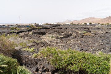 A sprawling volcanic terrain dominates the scene, with hints of buildings and mountains in the distance.