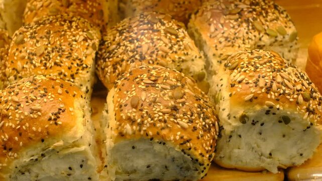 A row of bread with sesame seeds on top. The bread is on a wooden table