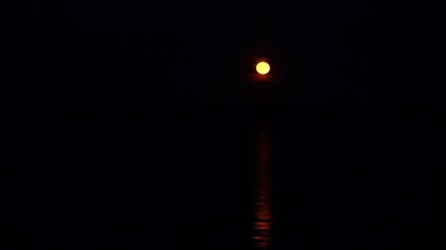 Red strawberry moon rises over the Greifswalder Bodden in June 2025. Mystical glow reflects on the water.  The video excerpt of 17 seconds is 85 MB in size. The frame rate is 50 pps.