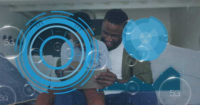 Smiling father and son exploring superimposed 5G data overlays on home sofa, with tablet computer