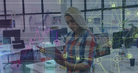 Holding tablet, woman wearing checkered shirt analyzing digital overlay in office, with monitors