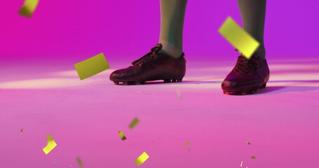 Showing athlete lower legs wearing green socks and black cleats on studio floor, with gold confetti