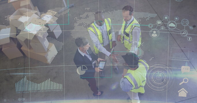 Collaborating warehouse team in neon vests analyzing map overlay on tablet inside distribution hub