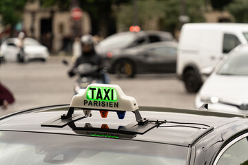 Green illuminated taxi sign on a Parisian cab, indicating availability for hire in the bustling city
