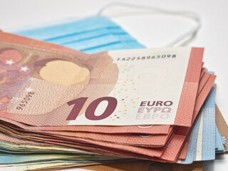 Obraz premium Closeup shot of euro money and face mask on white background