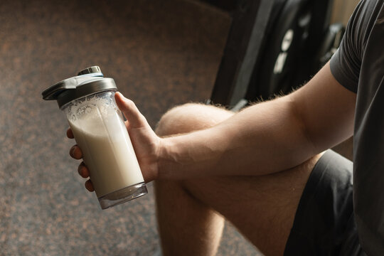Close up shot of man at gym holding protein shaker. Bodybuilder during strength training. Fitness healthy lifestyle concept. Supplement product, creatine, glutamine for workout.
