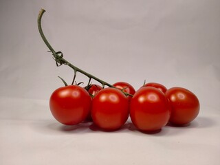 red ripe cherry tomatoes with a long stem, side view on a white background