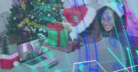 Smiling woman in Santa hat raising arm at home, with Christmas tree and laptop, copy space