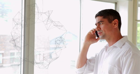 Mature man wearing white shirt talking on smartphone in office beside wireframe window, copy space