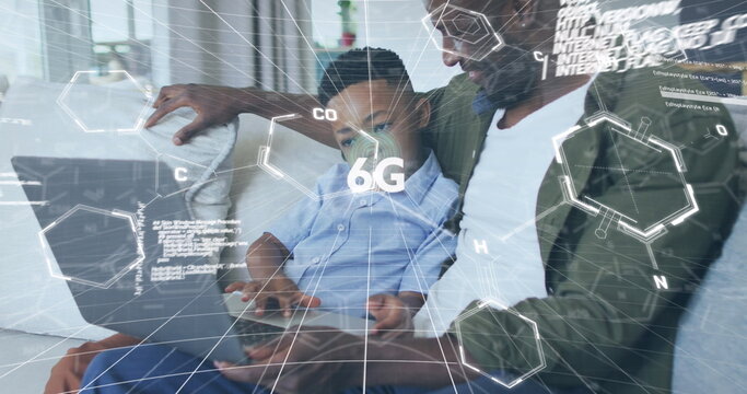 Guiding father and son tapping silver laptop trackpad in bright living room, with 6G graphics - Powered by Adobe