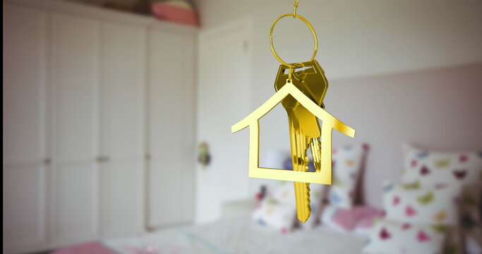 Displaying golden house-shaped keyring holding two brass keys above bed with cushions and wardrobe