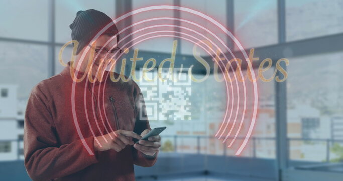 Man wearing beanie viewing AR rings and UnitedStates QR code with smartphone in office, copy space - Powered by Adobe