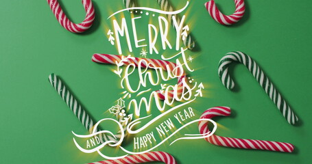 Displaying greeting reading MERRY Christmas and HAPPY NEW YEAR on green surface with candy canes