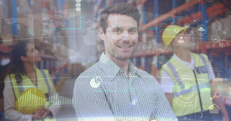 Smiling supervisor standing at distribution center with racks workers holding helmets under overlay