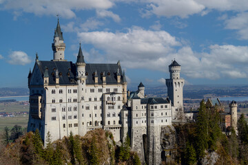 Fototapeta premium Imposing castle stands against a vibrant sky at midday, surrounded by lush greenery and distant mountains