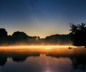 Closeup shot of a lake surrounded by forests under a sunset sky