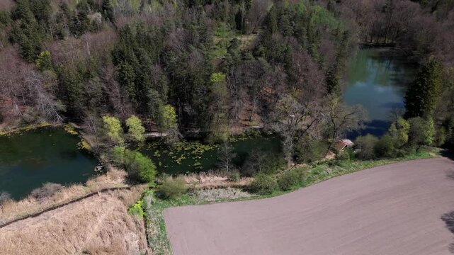 Stunning aerial view of Spiegelweiher serene lake chain near Grafing bei Muenchen, Bavaria, Deutschland. Crystal clear waters, lush spring greenery and trails create perfect scene for nature lovers. 
