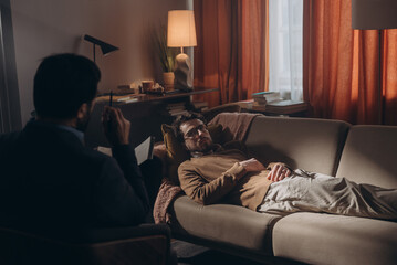 Obraz premium Man therapist holds pen while speaking to male patient during therapy session