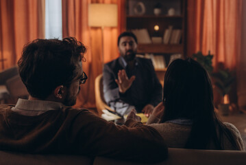 Naklejka premium Man therapist with notebook talks to married couple offering insights about family relationship. Male psychologist helps patients strengthen connection